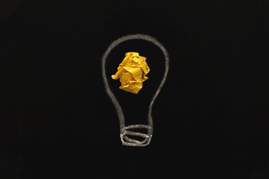crumpled yelllow paper laightbulb as a concept creative idea on a blackboard background