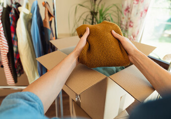 Pov view of man packing clothes into box for resale or donation.