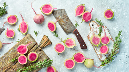 Sliced radish watermelon on the kitchen board. Dietary useful vegetables. On a gray stone background.