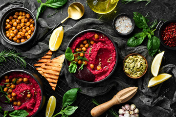 Beetroot chickpea hummus in a bowl. Red hummus. Healthy vegetarian food. On a concrete black background.