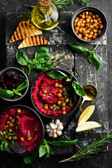 Healthy vegetarian food: Hummus. Beet and chickpea hummus in a bowl. On a concrete black background.