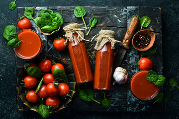 Homemade tomato juice in glass bottles. Top view. On a stone background.
