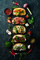 Set of colored sandwiches with tomatoes, prosciutto, vegetables and cheese on a black stone background. Bruschetta. Top view.