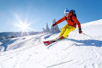 Skier skiing downhill in high mountains against blue sky.
