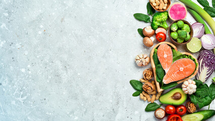 The concept of healthy food: nuts, salmon, avocados, spinach, mushrooms, berries. On a stone...
