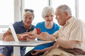 tre anziani seduti di fronte a un tavolino stanno per fare un acquisto via internet con carta di...