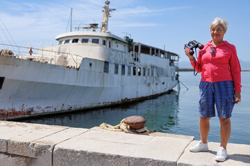 Donna con vestiti casual guarda dal binocolo vicino alla banchina di un porto 