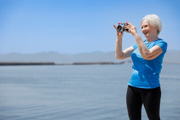 donna in abiti sportivi fa delle foto con un reflex analogica vicino al porto 