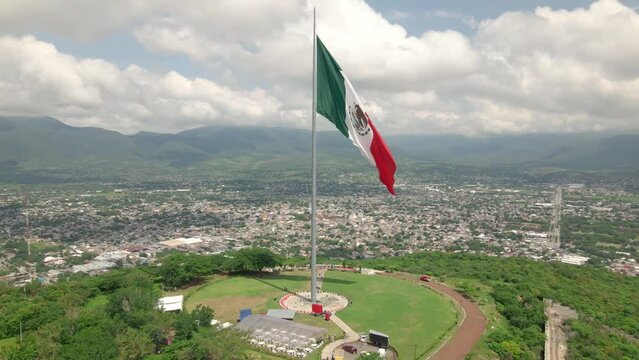 Slow aerial view of the waving Mexico Independence Declaration flag above Iguala