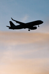 Fototapeta na wymiar Silhouette of airplane in the sky at sunset with dramatic clouds