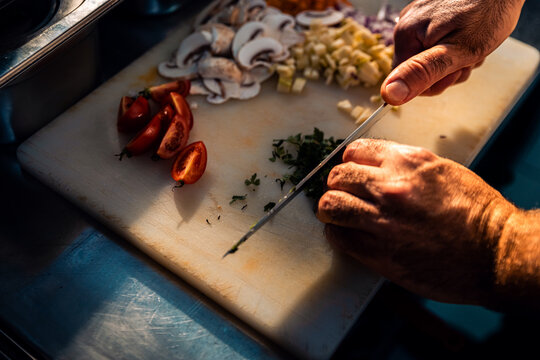 Close up of chef hands cooking in a commercial kitchen choping vegetable.