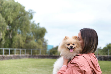 Girl hugging her pomeranian dog in a park.