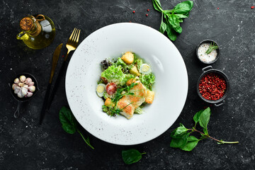 Traditional Caesar salad with chicken. On a black stone background.