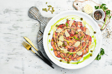 Salmon and tuna carpaccio with sauce and cheese on a white plate. Top view. Rustic style.