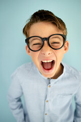 young cool boy with blue shirt, with big massive black glasses standing in front of blue background