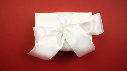 Gift white box with a bow on a red background. Holiday concept.Christmas. New Year.