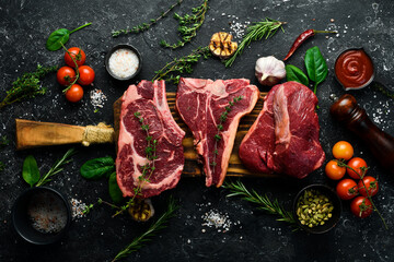 A variety of raw beef steaks for grilling with seasonings: T-bone, striploin steak, ribeye. Top...