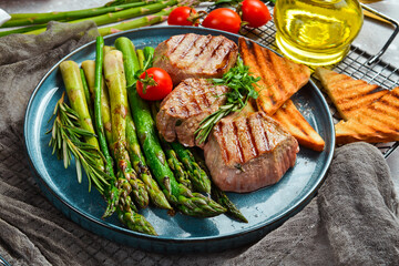 Steak. Veal medallions with asparagus, tomatoes and toast. On a black stone plate.