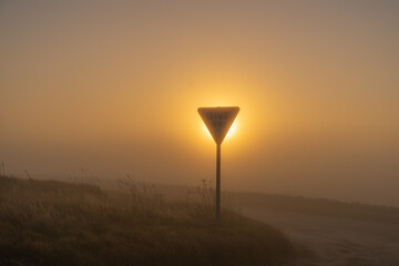 Give way sign on a moorland road on a foggy winter morning