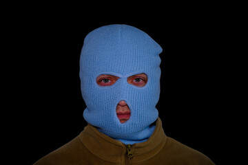 The face of a man in a blue balaclava isolated on a black background