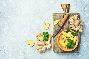 Slices of fresh ginger root on a wooden surface. Free space for text, on stone background.