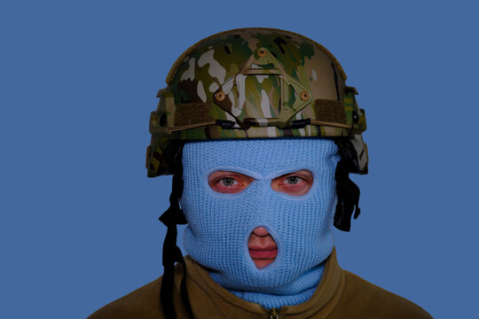 A man in a blue balaclava and a military helmet. Isolated on blue background