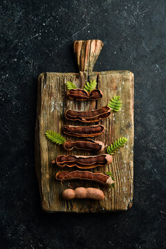 ripe tamarind on a kitchen wooden board. On a stone background. Top view.