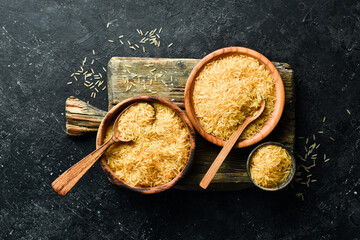 Organic rice groats in a wooden bowl. on a stone background. Healthy food.