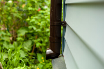 the lower part of a new plastic drain pipe on a country house or cottage shared by modern siding