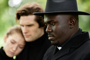 Side view portrait of African American priest holding ceremony at outdoor funeral