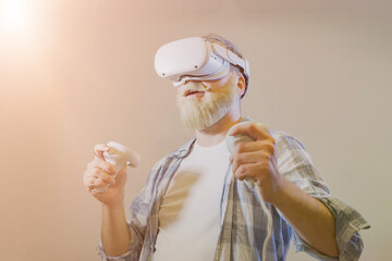 Elderly gray-haired mustache bearded man wear vr helmet gadget device equipment watching realistic experience experiencing virtual reality playing in video game in meta universe