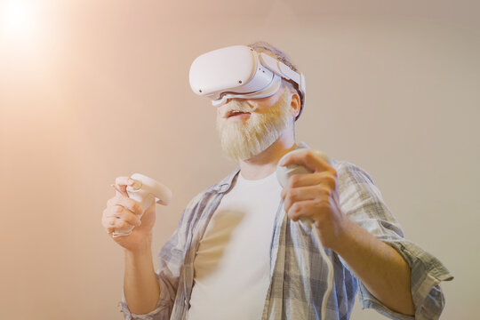 Elderly gray-haired mustache bearded man wear vr helmet gadget device equipment watching realistic experience experiencing virtual reality playing in video game in meta universe
