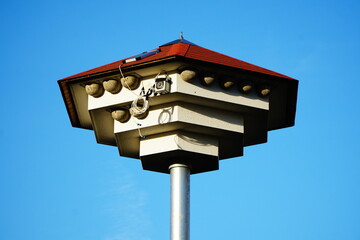 Man-made pentagonal house for swallows with red roof lit by the sun
