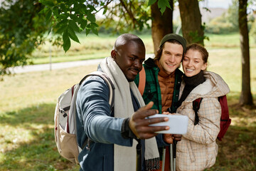 Group of smiling friends taking selfie photo in nature while enjoying hike together