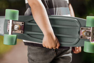 Close up picture of a kids hand holding a skateboard