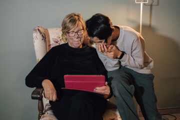 Girl laughing while playing with her grandmother on the tablet
