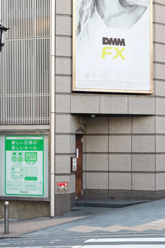 TOKYO, JAPAN - February 3, 2022: Billboard advertising DMM bitcoin services in Tokyo's Roppongi area. Tokyo Metropolitan Government poster by street has information advice on coronavirus rules etc.