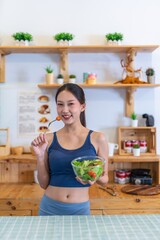 Young beautiful asian female adult lady in gym outfit after yoga exercise. Eat clean food salad with tomato for healthy and slim fit lifestyle.