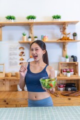 Young beautiful asian female adult lady in gym outfit after yoga exercise. Eat clean food salad with tomato for healthy and slim fit lifestyle.