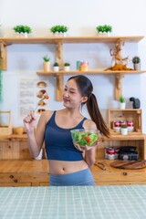 Young beautiful asian female adult lady in gym outfit after yoga exercise. Eat clean food salad with tomato for healthy and slim fit lifestyle.
