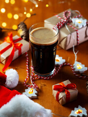 Christmas wooden table with gift boxes and a glass of stout beer