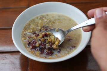 a close up of a bowl of green bean porridge and black sticky rice doused in coconut milk