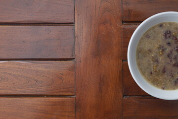 a close up of a bowl of green bean porridge and black sticky rice doused in coconut milk