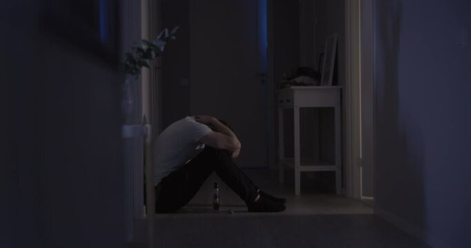 Depressed Man Sits on corridor floor in the dark due the Drugs and Alcohol addictions