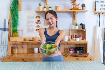 Young beautiful asian female adult lady in gym outfit after yoga exercise. Eat clean food salad with tomato for healthy and slim fit lifestyle.