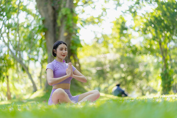 Fitness woman doing yoga in park, calm and relaxing women's happiness blurry background Asian woman meditating while practicing yoga concept of freedom peace and relaxation healthy