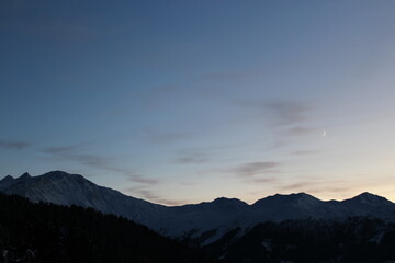 Sunset over Swiss alpine mountains. Silhouette of a mountain range against sky at sunset with...