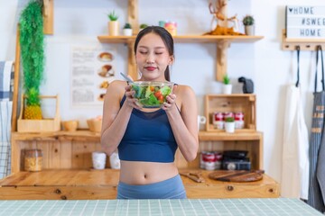 Young beautiful asian female adult lady in gym outfit after yoga exercise. Eat clean food salad with tomato for healthy and slim fit lifestyle.