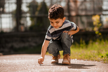 Fototapeta premium Boy drawing something on the ground