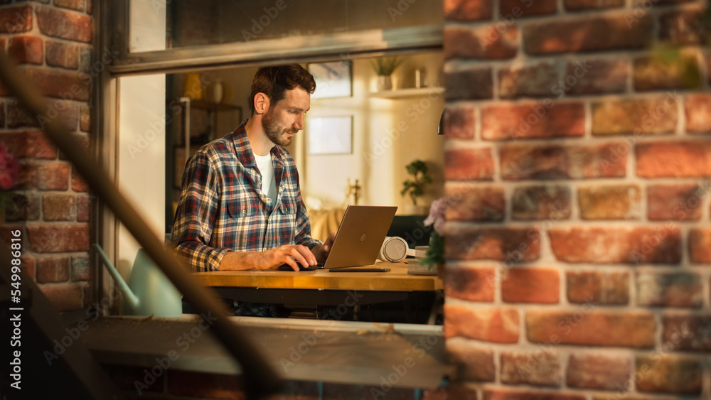 Aufkleber Male Software Engineer Coding on Laptop Computer, Working in Modern Apartment. Professional IT Specialist Designing Application. Freelancer Doing Remotre Work. View From Outdoors into Window.